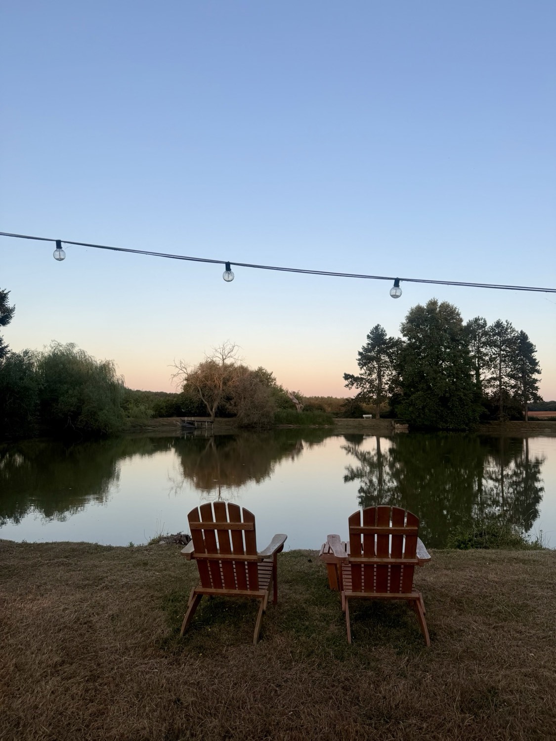 Twee fauteuils aan de oever van de privévijver, bij zonsondergang