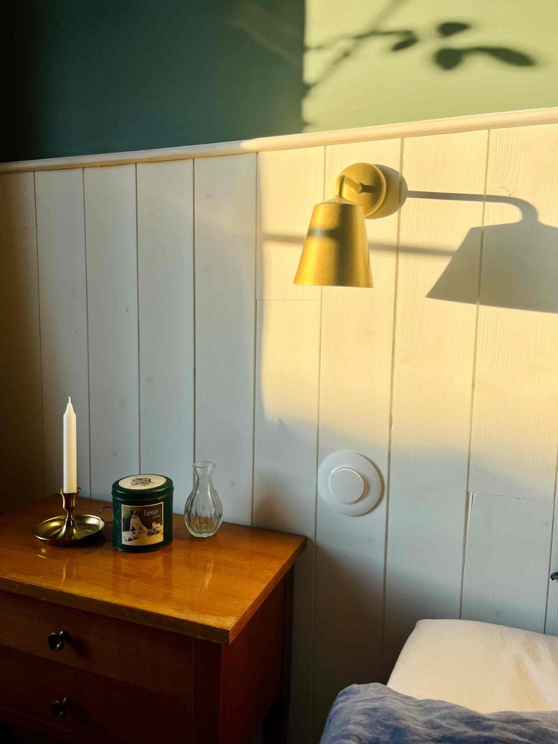 Lichte slaapkamer met gouden wandlampen en witte lambrisering