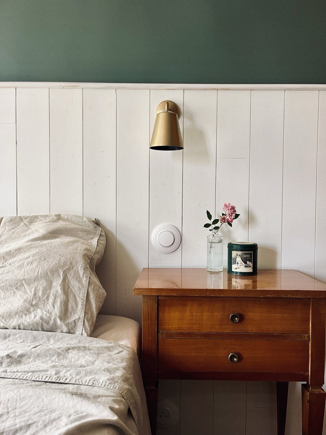 Gezellige slaapkamer, met messing wandlamp en gebloemd nachtkastje